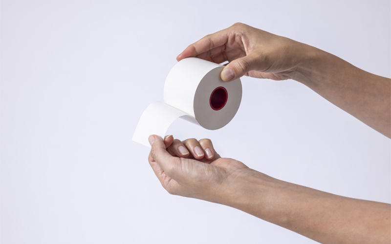 Two hands holding a roll of linerless labels 