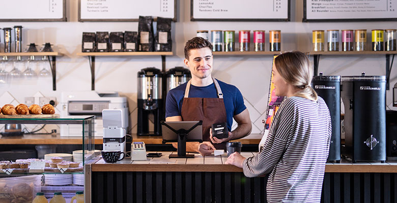 Mies barista palvelee kahvilassa naisasiakasta