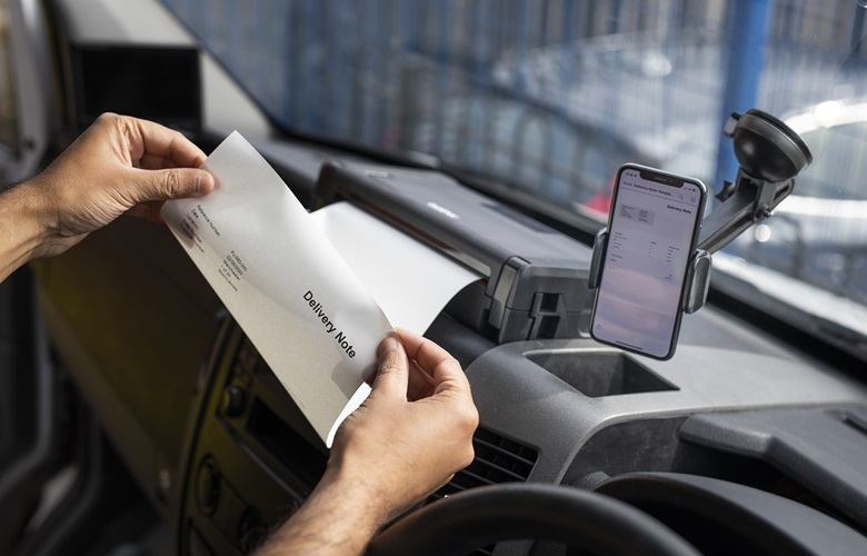 Keltaiseen liiviin pukeutunut mies tulostaa autonsa kojelautaan kiinnitetyllä PJ-mobiilitulostimella