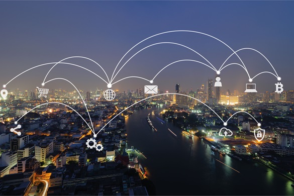Photograph of a cityscape that is interconnected by icons such as a laptop, letter, a cloud, and cogs